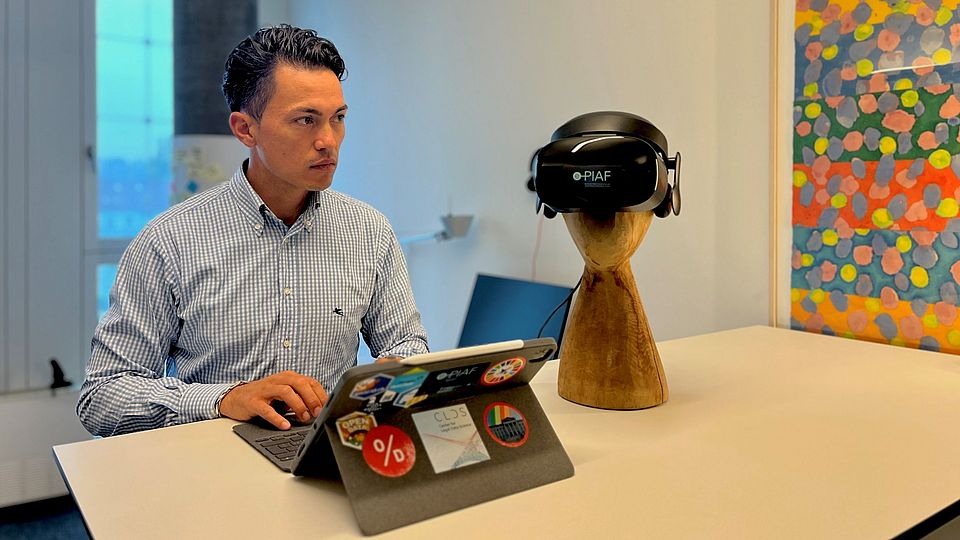 Apollo Dauag steht am Stehpult mit einem Laptop und einer VR-Brille neben sich.