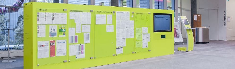 Anzeigetafel in gelber Farbe mit aktuellen Informationen zur Juristischen Fakultät in deren Eingangsbereich.
